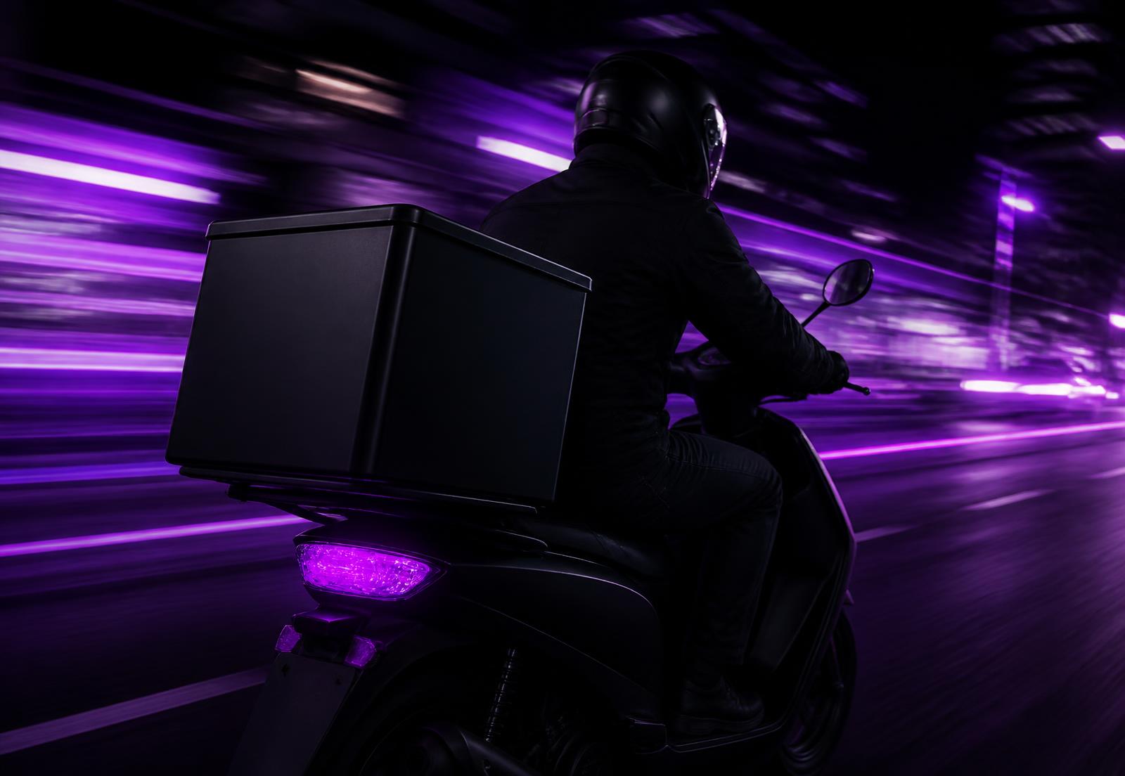 Motorcycle courier riding through town with a delivery box
